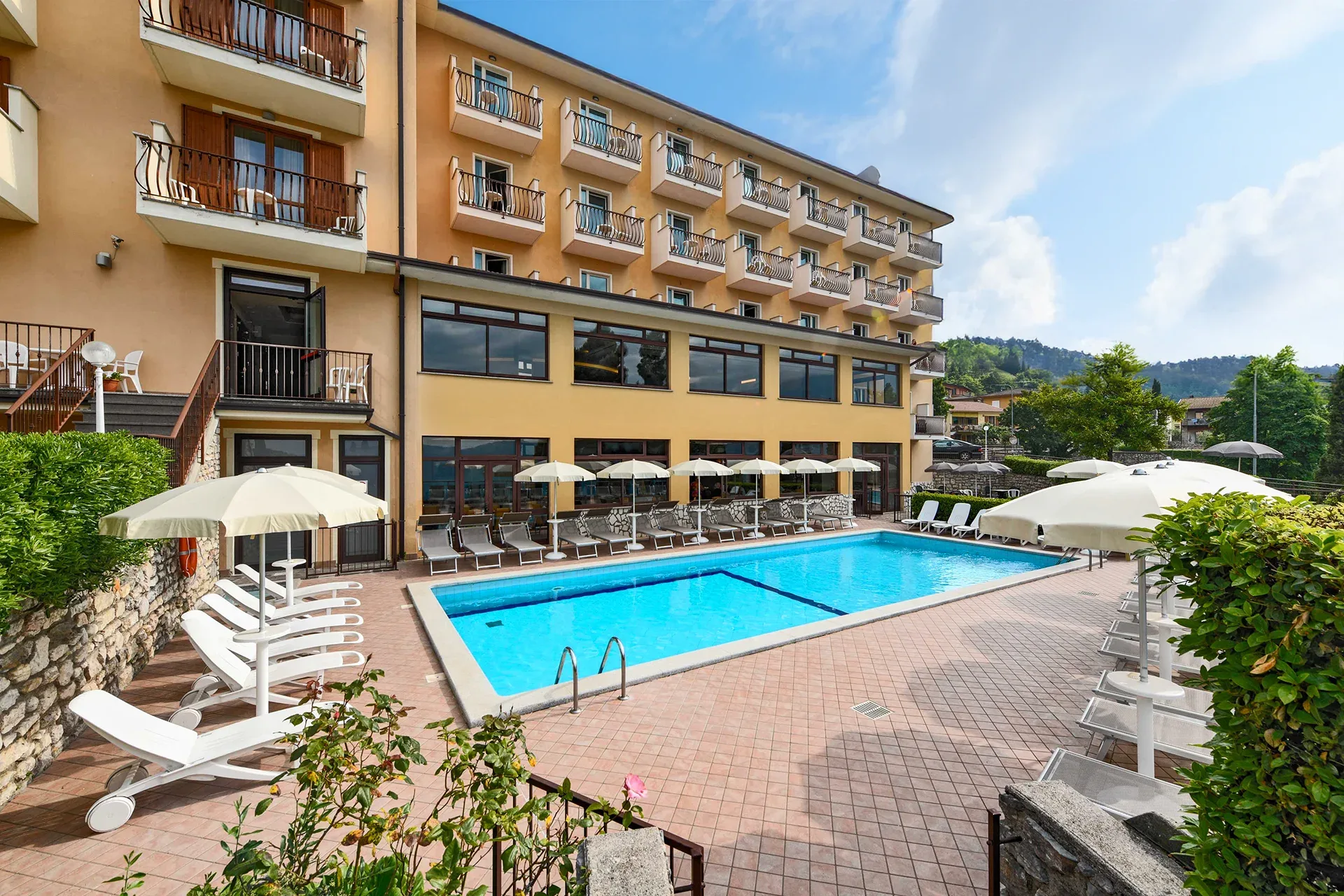 Hotel outdoor pool with sun loungers and umbrellas near Lago di Garda