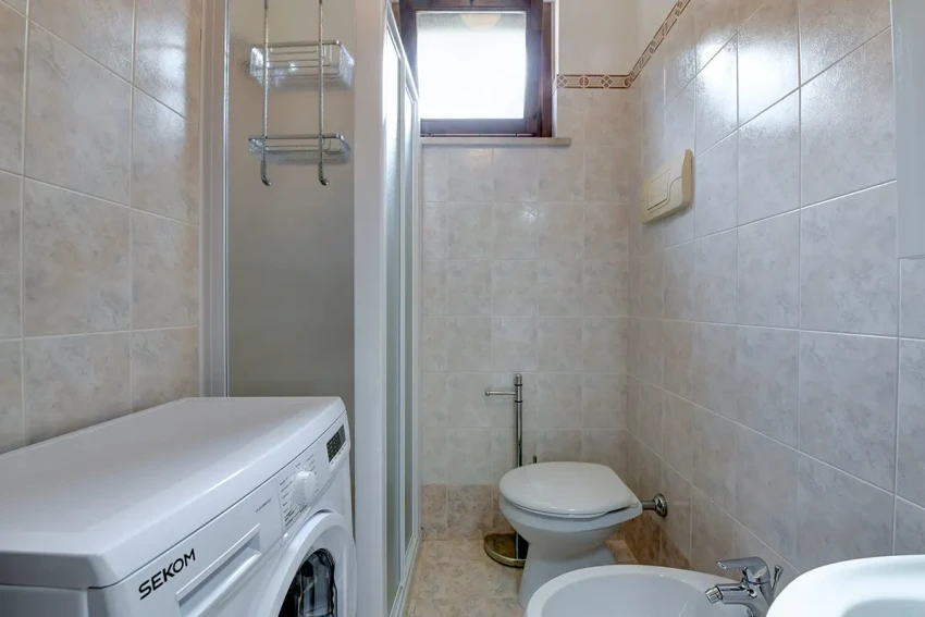 Kleines Bad mit Dusche, Waschmaschine, WC und Bidet nahe dem Gardasee.
