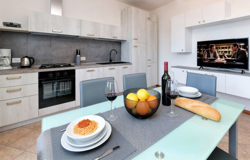 Modern kitchen with set table, spaghetti, red wine and fruit near Lake Garda