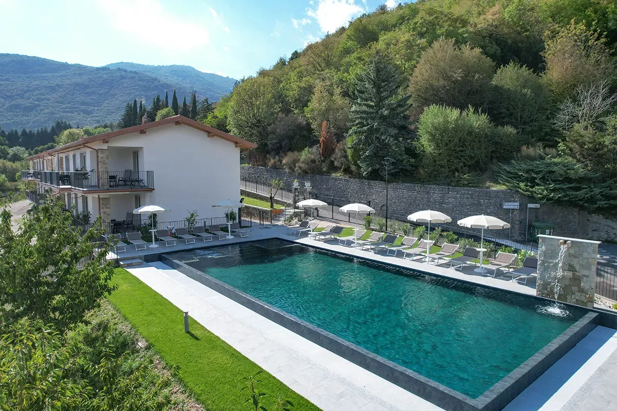 Outdoor hotel pool with sun loungers and hillside near Lago di Garda.