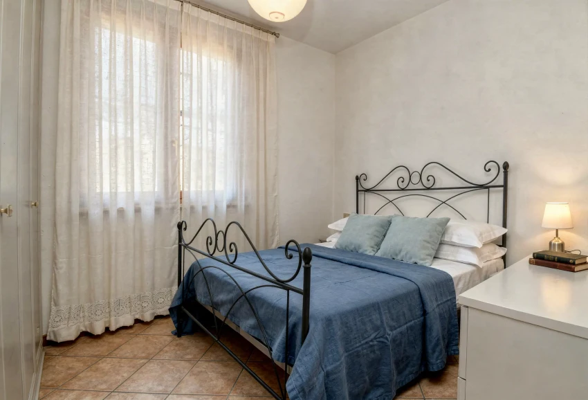 Helles Schlafzimmer mit Eisenbett und blauer Bettwäsche, Gardasee