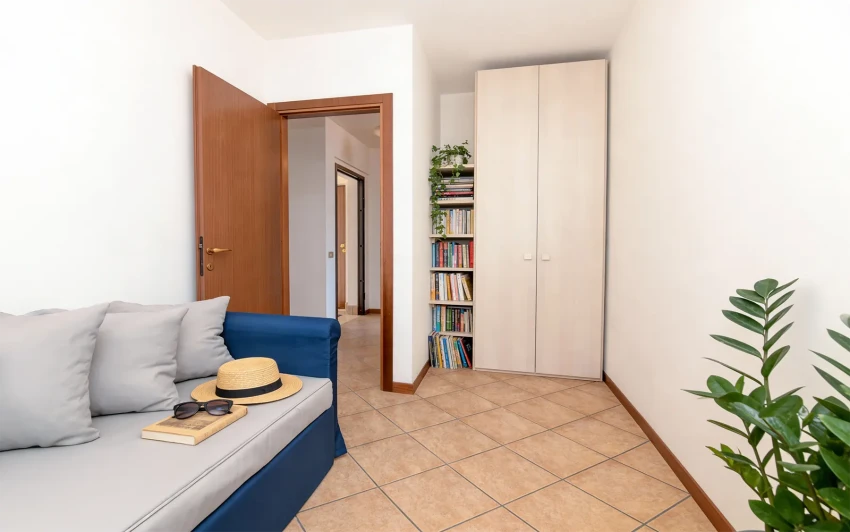 Helles Wohnzimmer mit blauem Sofa, Bücherregal und Schrank nahe dem Gardasee